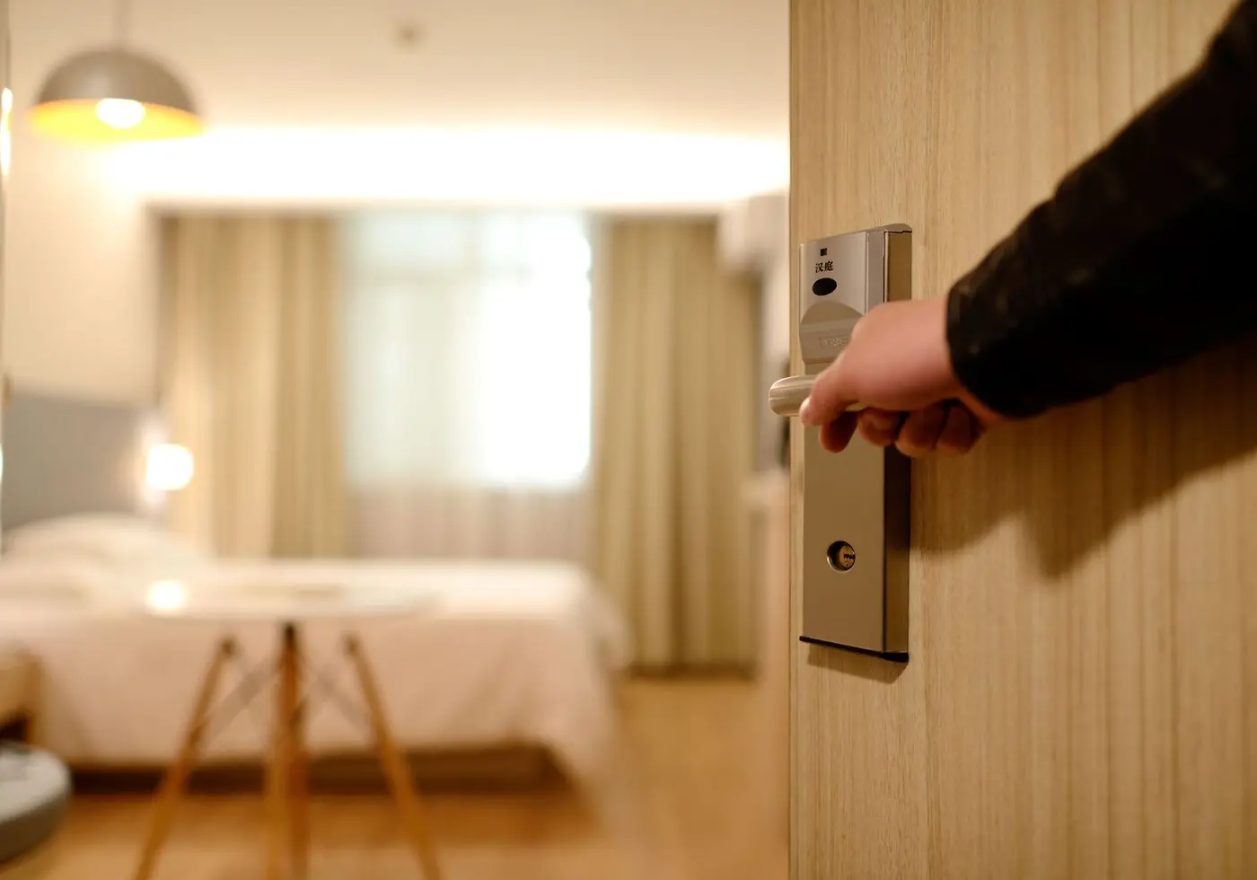 Porte d'une chambre qui s'ouvre sur un lit prêt pour l'arrivée des voyageurs