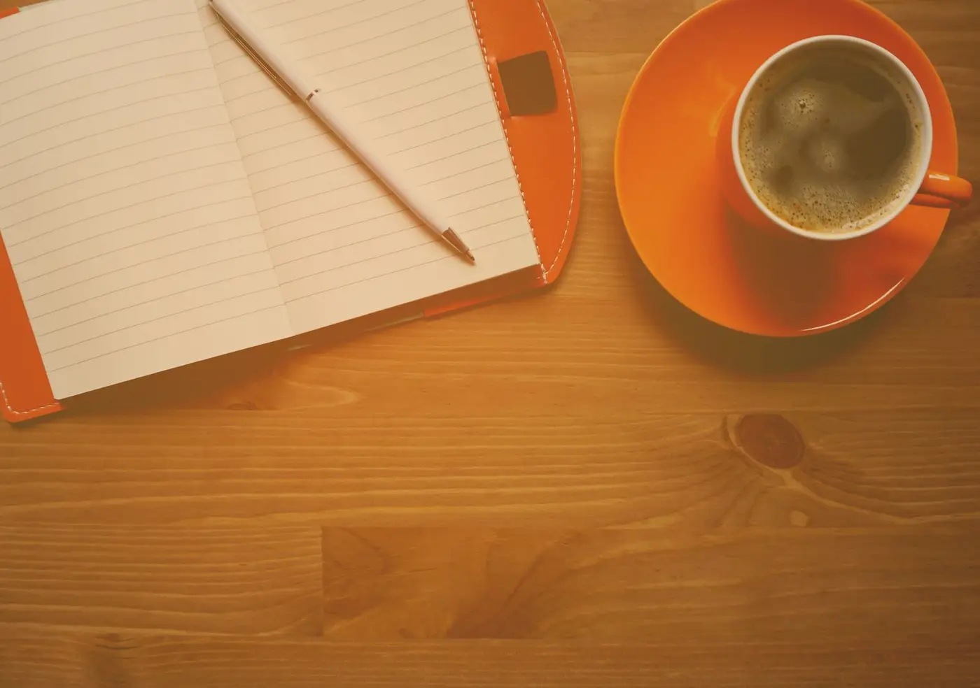 Carnet ouvert et tasse de café posés sur une table en bois