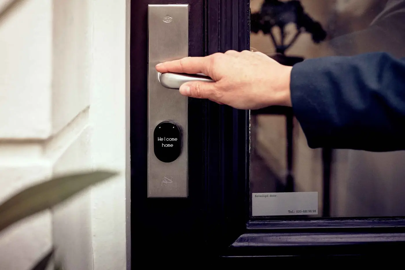 Une main ouvre une porte équipée d'une serrure connectée